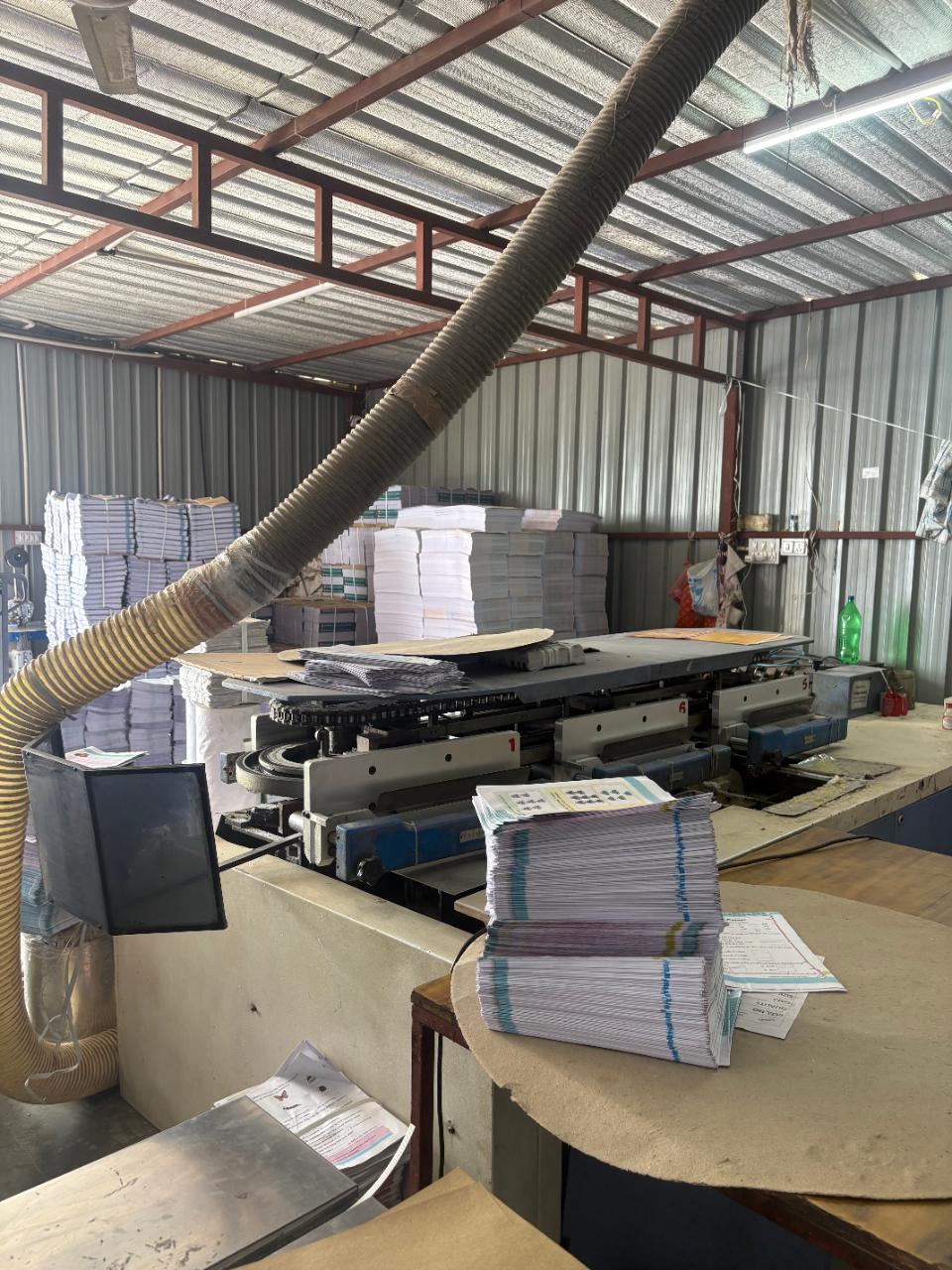 The bindery and stitching line, with pallets of printed sections behind.